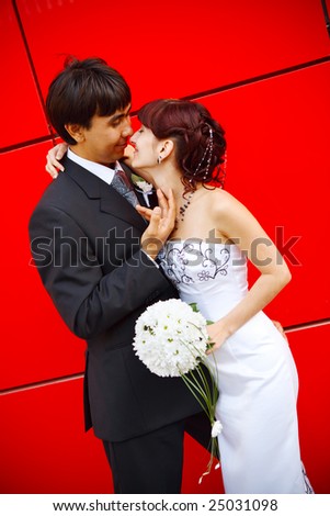 funny bride and groom by the red wall