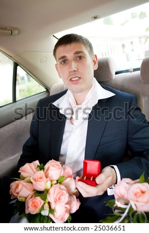 groom with rings and flowers in the car