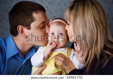 mom and dad kiss their daugther