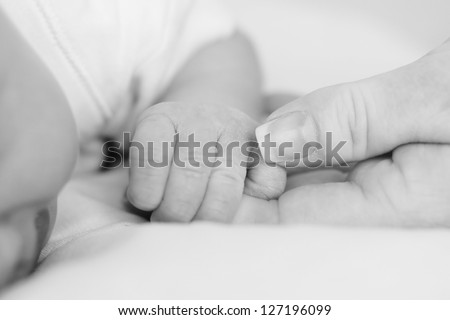 Loving hands. A mother\'s hand holding her newborns hand in hers. Tiny fingers curled around mothers finger.