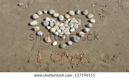 Love heart made of pebbles on a sandy beach. the word Love spelt out in stones.