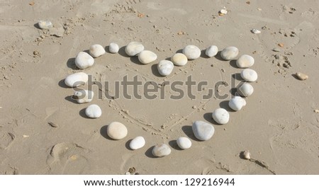 Love heart shape on sand made out of white pebbles, symbol of love