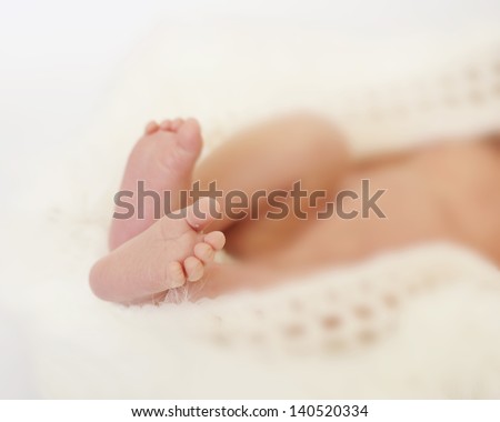 Close up of newborn baby\'s feet, soft focus on rest of baby.