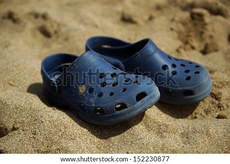 Beach shoes on pale sand, typical summer image.