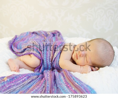 Tiny Sleeping Newborn Baby covered with rich purple coloured wrap