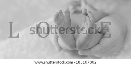 Tiny newborn baby feet in V shape spelling the word LOVE, black and white image