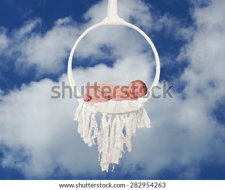 Sleeping newborn baby lay in dreamcatcher against blue sky and clouds