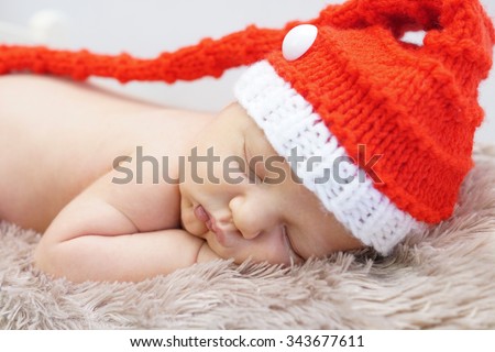Tiny sleeping newborn baby boy wearing Santa hat