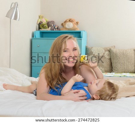 Smiling embracing mom with her baby lying in bed