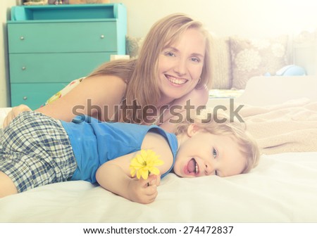 Smiling embracing mom with her baby lying in bed
