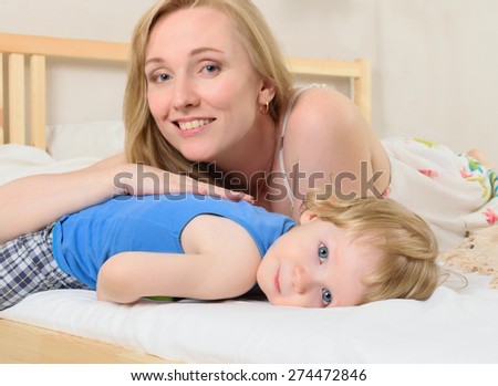 Mom blonde lying in bed with his little baby