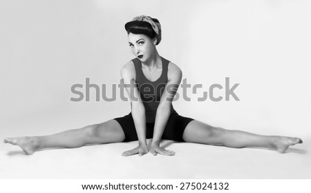 Famous retro pose foto. brunette in a blue shirt with a scarf on her head and hair in a retro style sitting on the splits