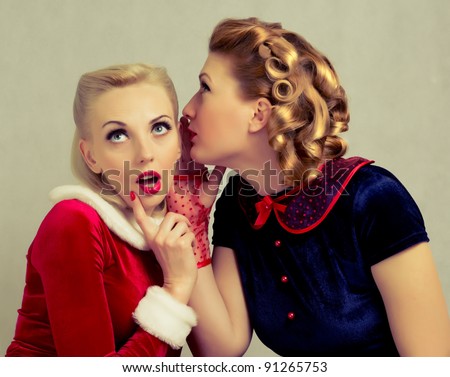 blonde girl whispers to her friend's ear