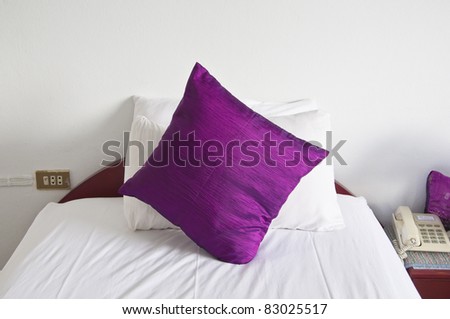 style bedroom interior with single  purple pillows on white wall