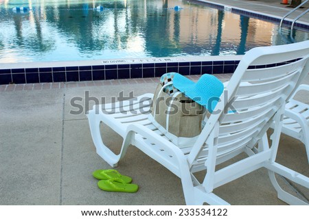 White deck chairs by a swimming pool with pool accessories