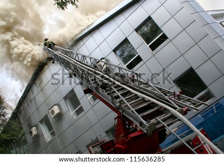 Building on fire. firefighter puts out a fire while on a ladder