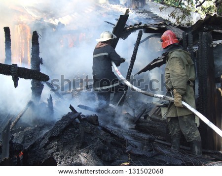 Smoldering remains of a ghetto house with a fireman spraying water firefighters extinguish a fire in an apartment house