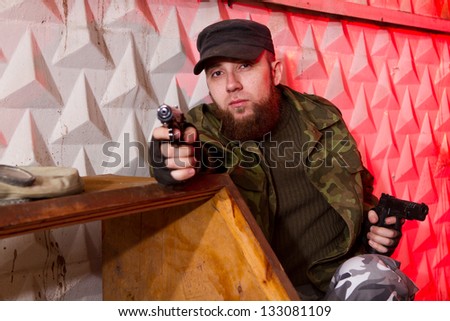 young bearded terrorist with a gun in the stroma of a dilapidated shelter, the basement of the old building