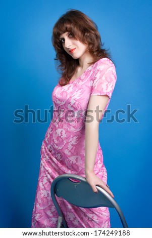 portrait of a beautiful young brunette in a pink dress on a  blue background