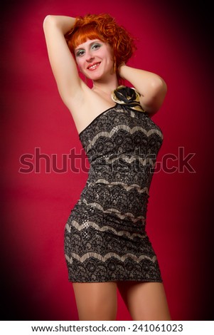 beautiful young red-haired girl  in an elegant dress on a red background