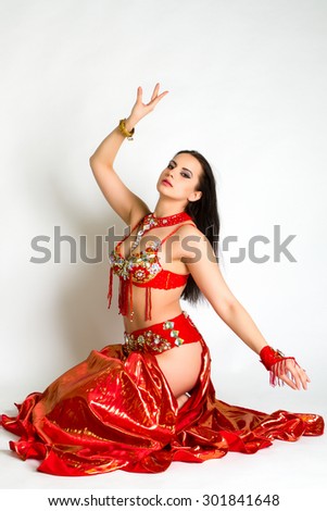Beautiful young girl in a red suit oriental dance in motion isolated on white background