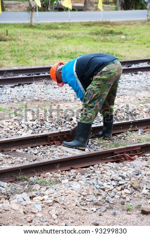 Railroad worker fixes a screw on the rails