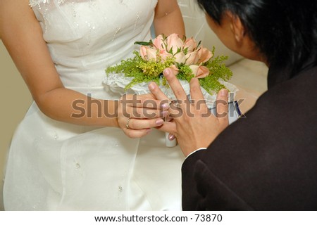 Bride putting wedding ring on groom\'s finger