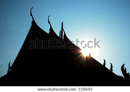 Wat Phra Kaew temple (Bangkok) in silhouette against the sun