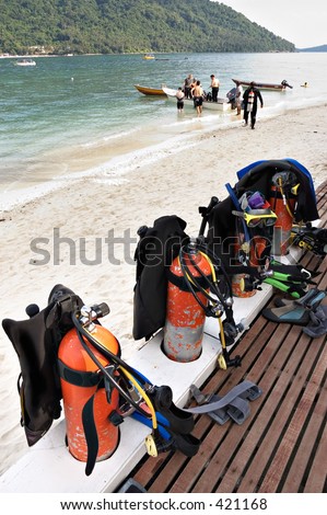 Scuba tanks with divers in the background getting onto a boat for a dive