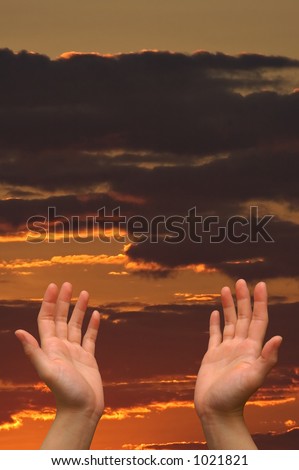 Hands reaching to heaven, on a cloud-filled orange sunset sky background