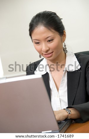 Asian lady in business attire working on notebook pc