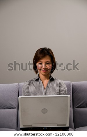 Asian lady in business attire, working on a notebook computer