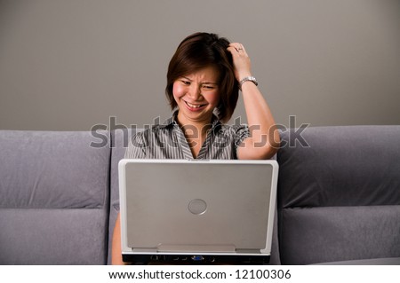 Asian lady in business attire, looking frustrated with a notebook computer