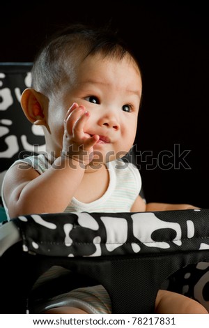 Six month old South East Asian Chinese baby girl sitting in a high chair