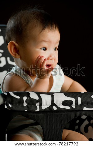 Six month old South East Asian Chinese baby girl sitting in a high chair