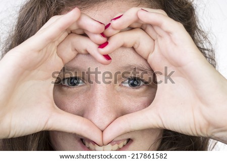 Teen with her hands held in a heart shape over her face