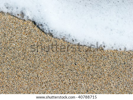 White sea foam on a yellow brown sand grains