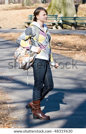Young teenager girl standing outside on the street holding a book bag