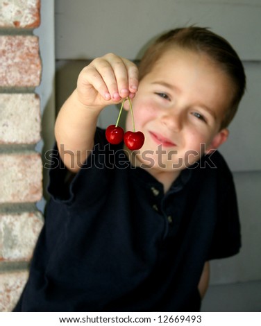 Boy holding out nice red cherries for you to see