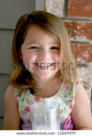 A very happy and very healthy girl holds a fresh glass of milk