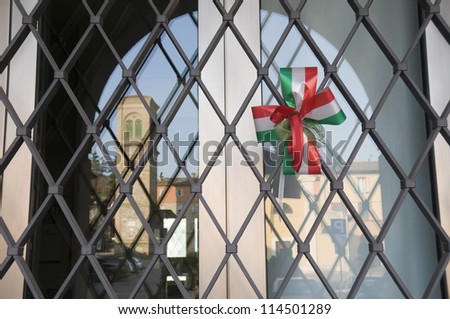 Ornamental bow with Italian flag colors on the grate of a window