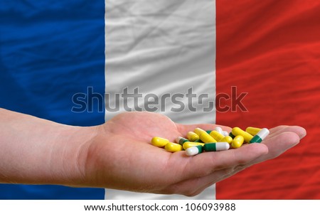 man holding capsules in front of complete wavy national flag of france symbolizing health, medicine, cure, vitamines and healthy life