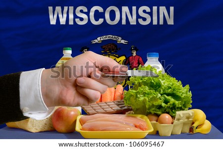 man stretching out credit card to buy food in front of complete wavy american state flag of wisconsin