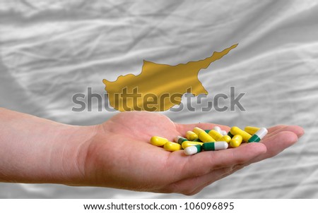 man holding capsules in front of complete wavy national flag of cyprus symbolizing health, medicine, cure, vitamines and healthy life