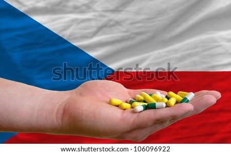 man holding capsules in front of complete wavy national flag of czech symbolizing health, medicine, cure, vitamines and healthy life