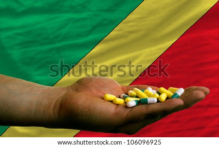 man holding capsules in front of complete wavy national flag of congo symbolizing health, medicine, cure, vitamines and healthy life