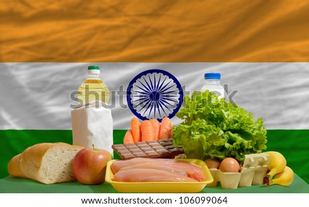 complete national flag of india covers whole frame, waved, crunched and very natural looking. In front plan are fundamental food ingredients for consumers, symbolizing consumerism