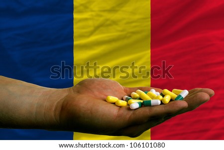 man holding capsules in front of complete wavy national flag of chad symbolizing health, medicine, cure, vitamins and healthy life