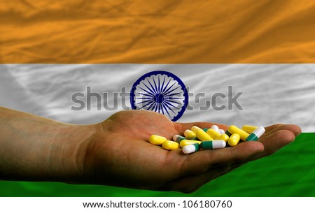man holding capsules in front of complete wavy national flag of india symbolizing health, medicine, cure, vitamins and healthy life