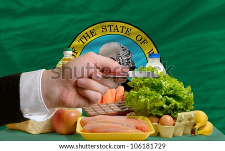man stretching out credit card to buy food in front of complete wavy american state flag of washington